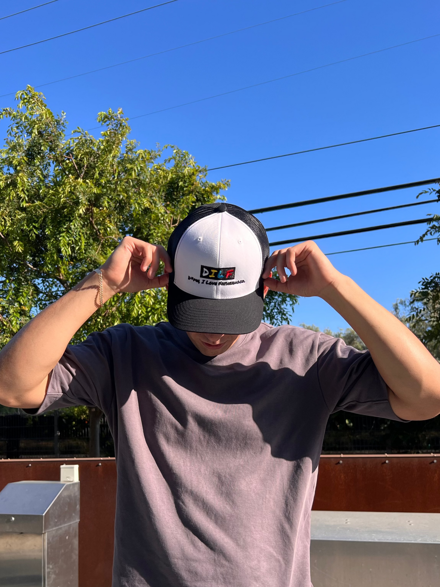 Person wearing DILF classic trucker hat outdoors.